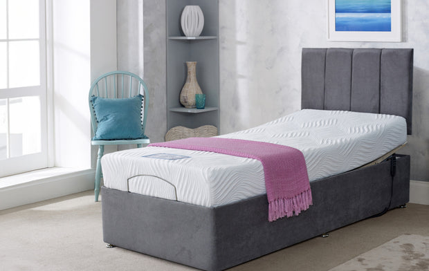 A grey adjustable bed positioned in a cozy room featuring a stylish blue chair nearby.