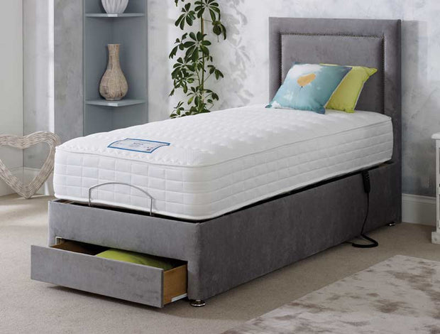 A grey adjustable bed featuring a comfortable mattress and convenient drawers for storage underneath.