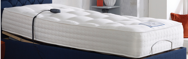 A cozy adjustable mattress resting on a bed with a stylish blue headboard, perfect for a good night's sleep.